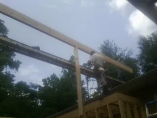 Carpenter setting a ridge beam over a new addition frame — Ice Dam Removal by Roofing Brothers in Belden