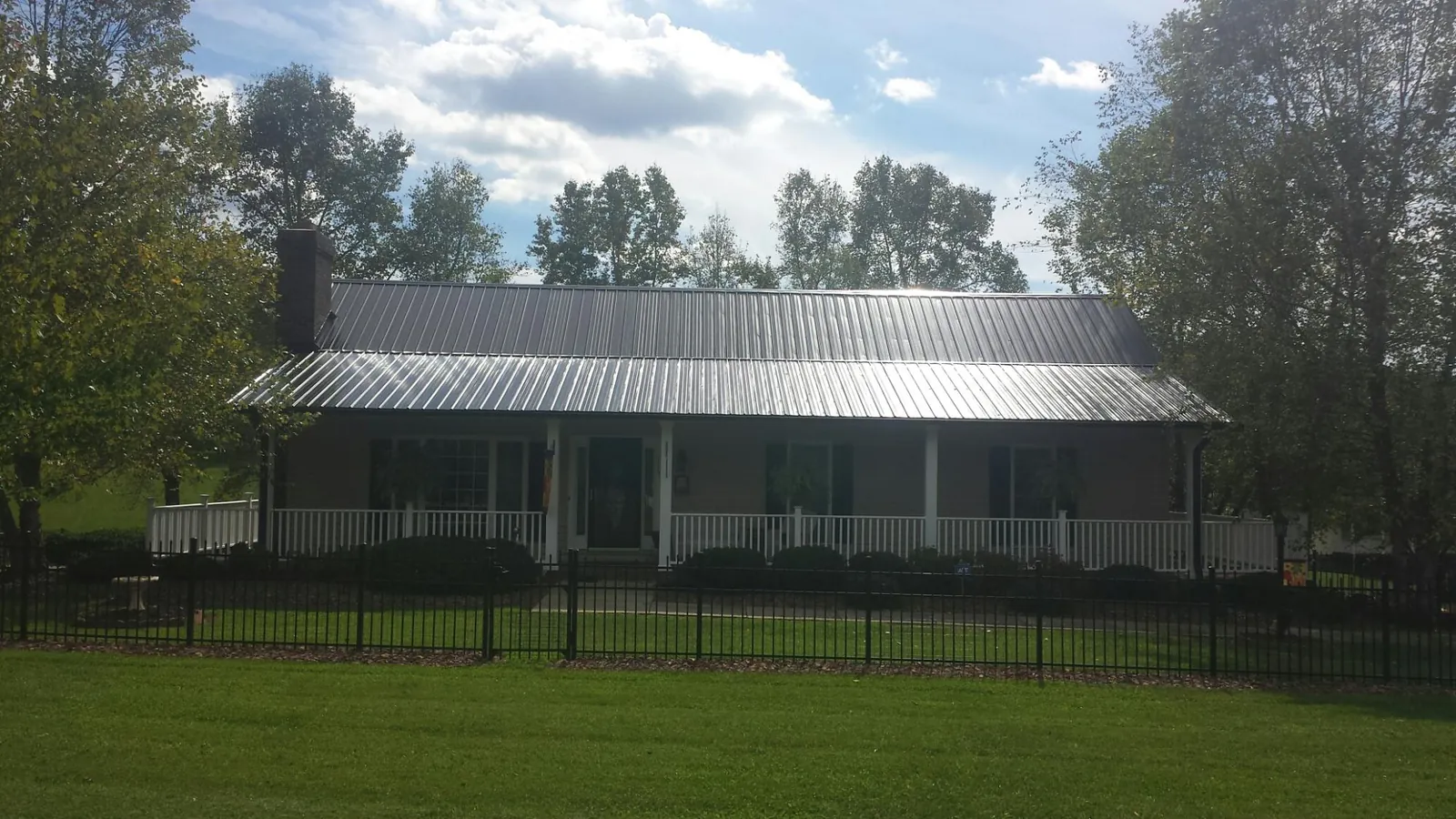 Gray metal roof on a brick ranch with a full width front porch — Gutter Guard Installation work by our crew in Belden