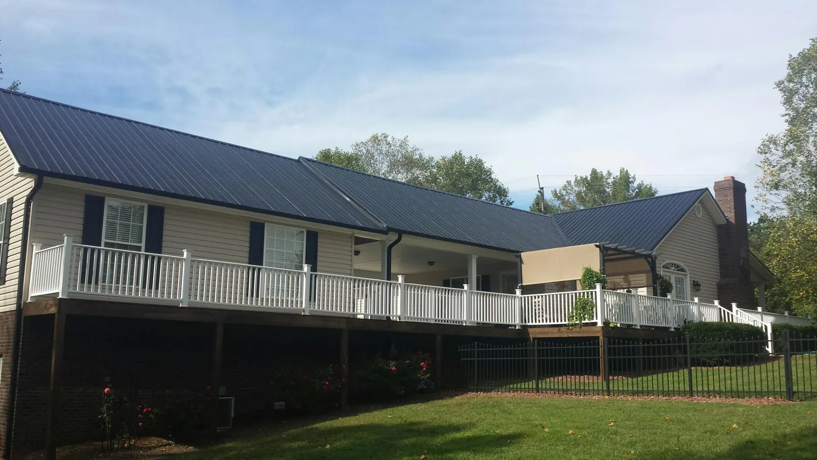 Black metal roof above a long white railed deck on a hillside home in Belden