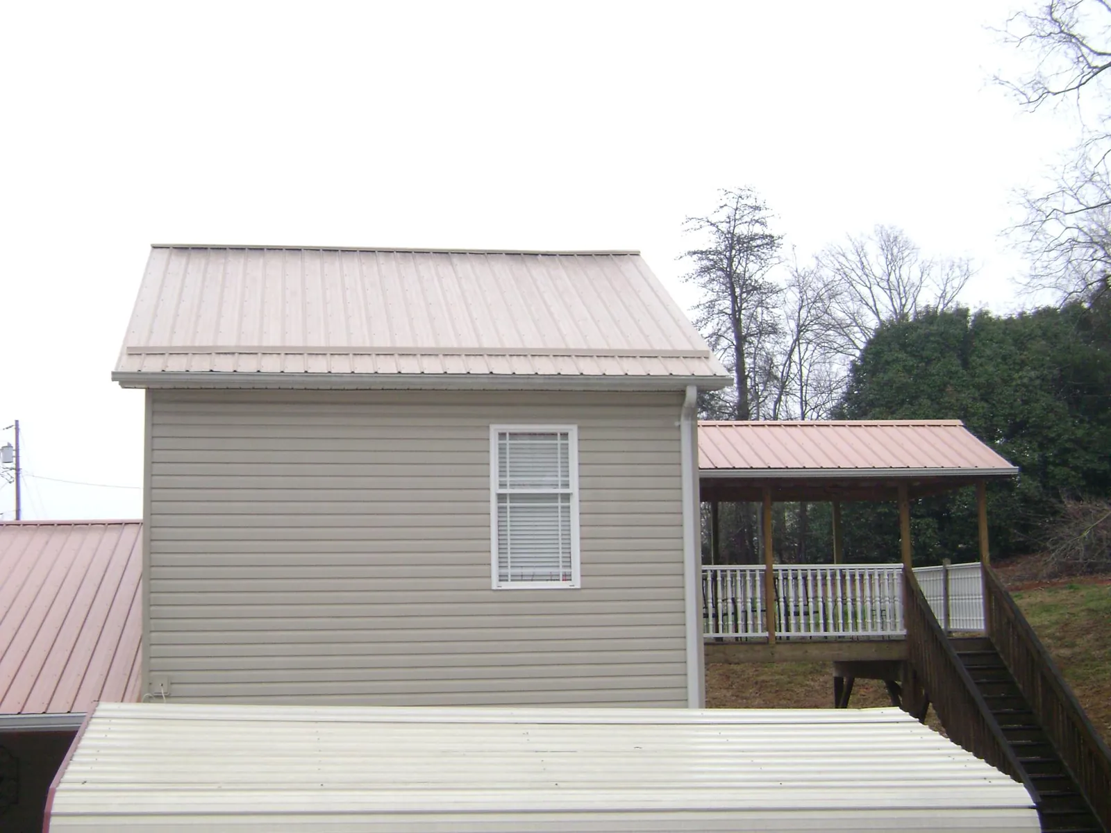 Tan metal roofs on a two story addition and attached porch, from a Roof Replacement job in Belden