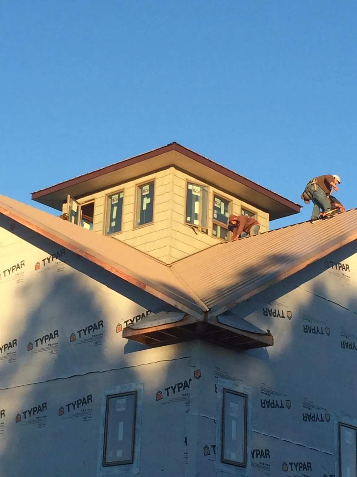 Roofers working around a rooftop cupola on a new metal roof at sunset — Roof Waterproofing in Belden by Roofing Brothers